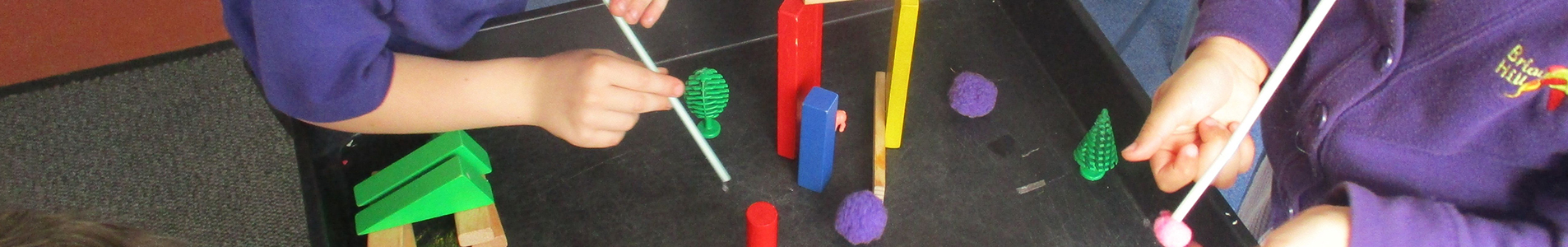 Two children picking up objects with straws