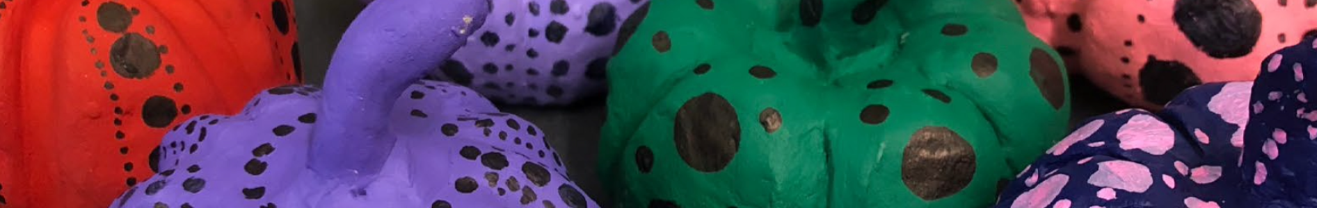 a close up image of small, colourfully painted pumpkins, decorated with various sizes of black dots