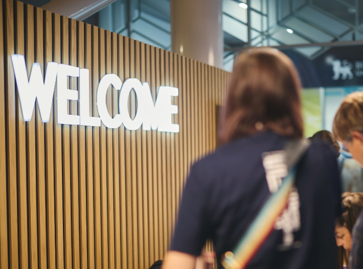 delegates arriving at the 2026 College Conference in Birmingham beside a large illuminated welcome sign