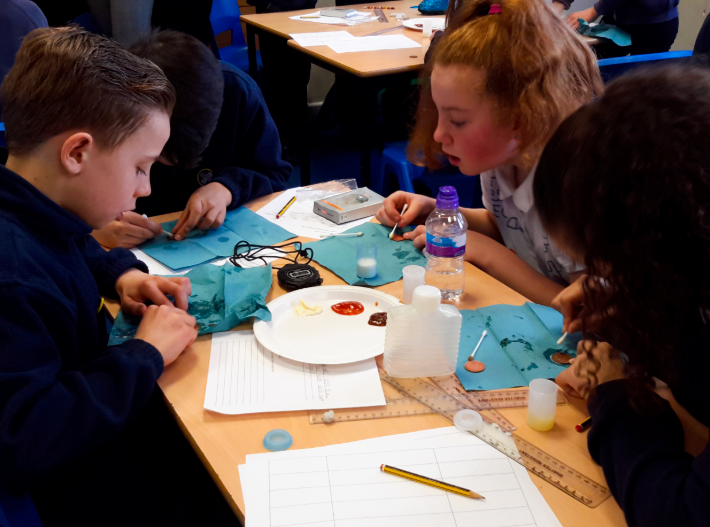 Primary school children investigating different methods for cleaning coins during a science activity